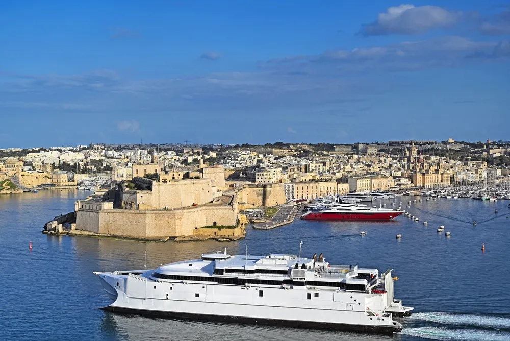 Un catamarano veloce nel Grand Harbour davanti a Fort St Angelo e Birgu